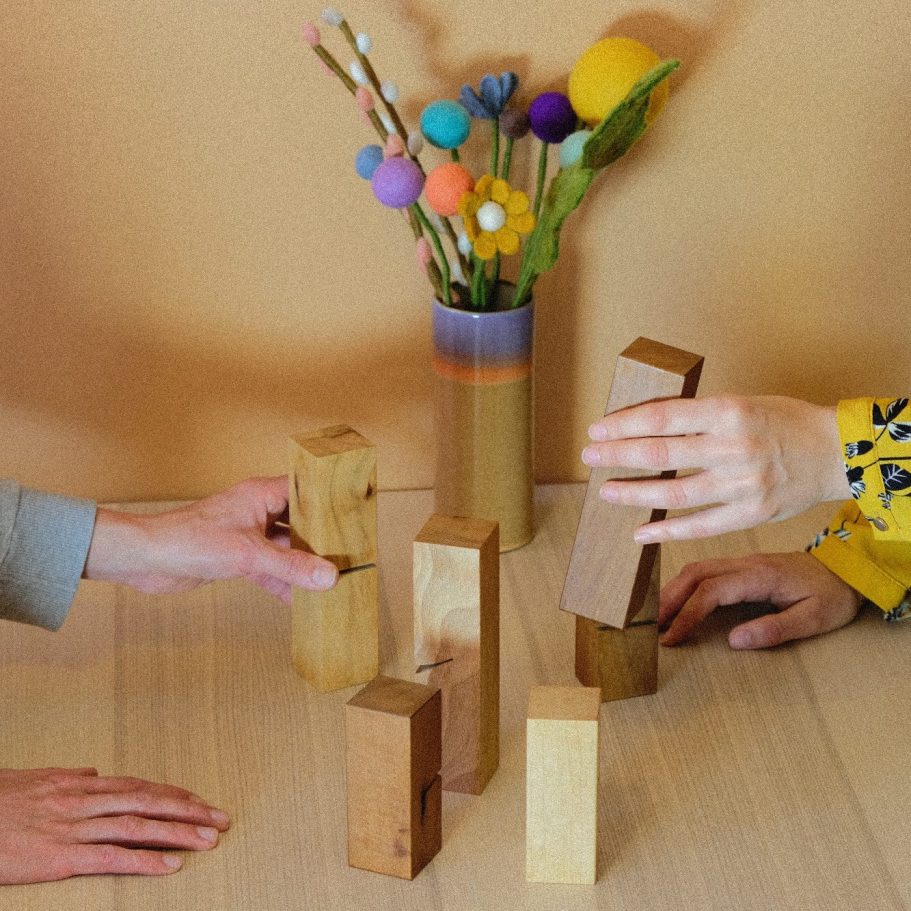 Einzelberatung Systembrett Zwei Hände stellen ein System mit Holzklötze auf dem Tisch im Beratungsraum.